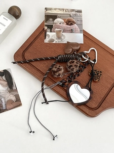 Detail of heart mirror pendant with leopard print pom poms and tortoise shell chain
