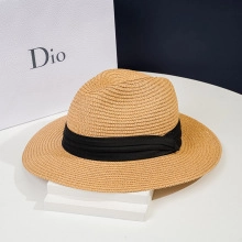 Detail of straw sun hat with wide black ribbon band on a minimalist display stand