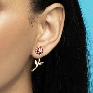 Close-up of flower stud earrings with pink and white stones on a model's ear