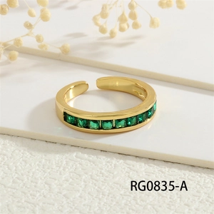 Detail of 18K gold plated ring with square green zircon stones on textured surface