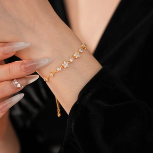 Detail of adjustable gold bracelet with star shaped zircons worn on female wrist