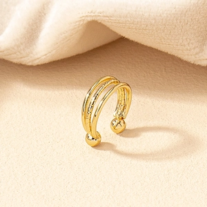 Macro shot of gold ear cuff featuring three minimalist parallel lines and polished spheres