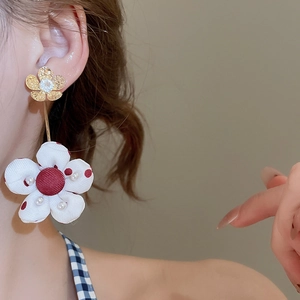 Detail of long floral drop earring with red polka dots and pearl on fabric flower