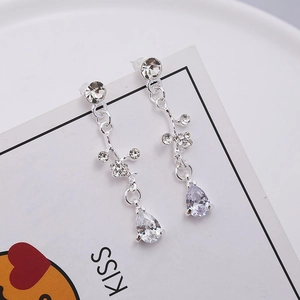 Detail of silver long tassel earrings with flower motifs and pear-shaped drop crystals