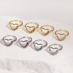 Détail de bagues cœur plaquées or 14k avec zircons colorés sur fond de pierre