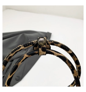 Detailed macro view of leopard print cylindrical handle and dark gray metal snap fastener