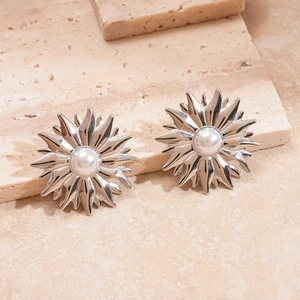Detail of silver sunflower earrings with white pearls on a natural stone base