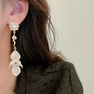 Close-up of model wearing long tassel pearl shell earrings with zircon flower detail