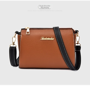 Detail of brown litchi pattern leather with white stitching and golden metal logo