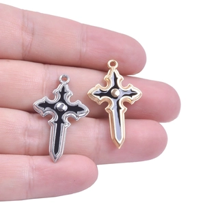 Detail of hand holding gold and silver gothic cross pendants with black enamel finish