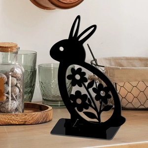 Detail of hollowed-out black metal Easter bunny ornament with floral patterns on wood base