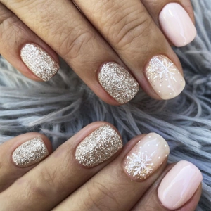 Detail von glitzernden Gold- und Nude-Nägeln mit Schneeflocken auf Pelzhintergrund