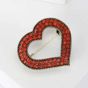 Macro shot of a red beaded heart brooch with vintage gold metal setting on white