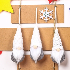 Close-up of three knitted Christmas gnomes with grey plush bodies and white pointed hats