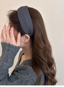 Detail of wide grey fabric headband worn with golden ring and hoop earrings