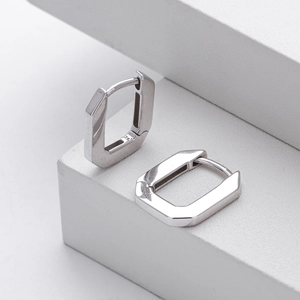 Macro shot of geometric octagonal S925 sterling silver hoop earrings on a minimalist white stand