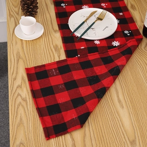Détail d'un chemin de table de Noël à carreaux rouges et noirs avec motifs de flocons