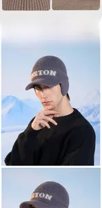 Detail of a dark gray knit beanie with ear flaps and white plush BOSTON lettering