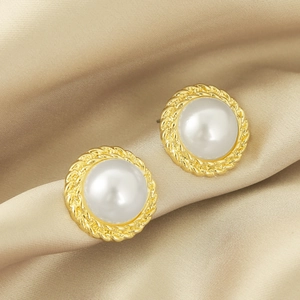 Close-up of vintage faux pearl earrings with twisted gold border on silk background
