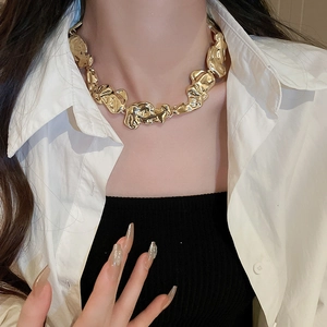 Detailed view of irregular molten texture gold necklace worn by a fashion model