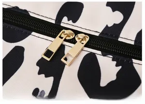 Detail of premium gold-plated dual zippers on cow print waterproof oxford travel bag