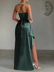 Detail of elegant dark green satin evening gown with cross back straps and side high slit