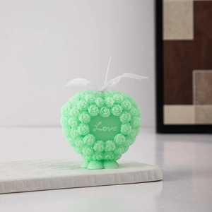 Close-up of mint green heart candle with rose relief and Love text detail