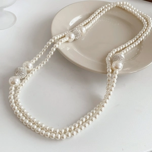 Close-up of double-layer pearl necklace with sparkling diamond-studded spheres on ceramic plate