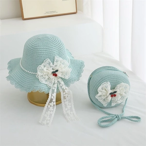 Detail of light blue straw sun hat and matching crossbody bag with lace bow and cherry decor