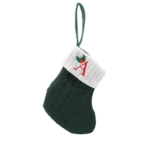Green knit Christmas stocking with white cuff and red embroidered letter A on white backdrop
