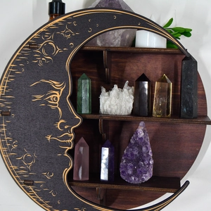 Deep brown moon-shaped wooden shelf with carved crescent face holding crystals and candles