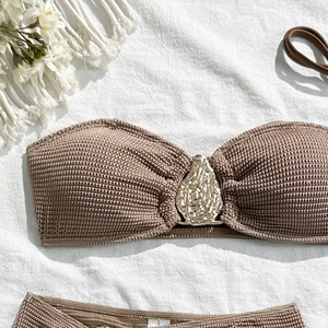 Detail of coffee-colored knit bikini top with a golden metallic ring ornament