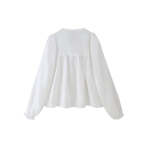 Blouse blanche ample en coton avec poignets à volants et détails plissés au dos