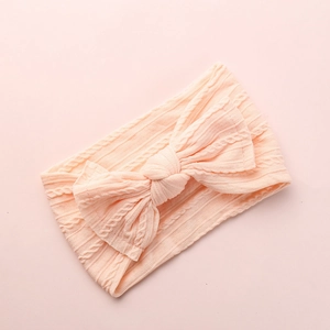 Detailed macro view of a peach jacquard nylon baby headband with large soft bow
