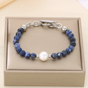 Detailed shot of blue textured beads and pearl bracelet with metal OT buckle on jewelry box