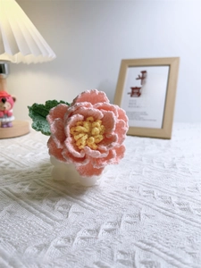 Detailed view of hand-crocheted pink peony with yellow stamen in white textured base