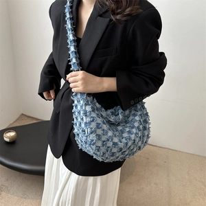 Blue denim tote bag with plaid weave and frayed texture worn by model in suit