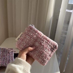 Detail showing pink and white tweed weave texture and smooth zipper on the mini pouch