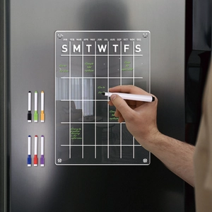 Close-up of hand writing on a magnetic clear acrylic monthly calendar board for refrigerators