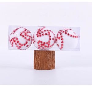 Dettaglio di tre palline di Natale in velluto bianco con strass rossi su base in legno