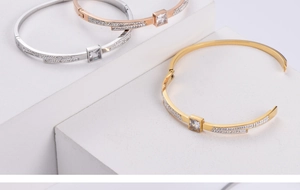 Close-up of gold, rose gold and silver bangles with square zircon on white stone
