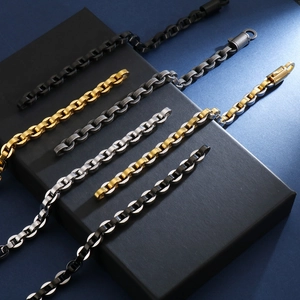 Gros plan de bracelets à maillons ovales en acier inoxydable or, argent et noir sur coffret