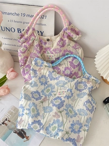 Floral canvas tote bags with daisy prints and colorful braided handles in purple and blue