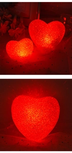 Macro shot of two heart-shaped glowing red night lights with textured surface on star mesh