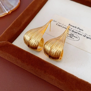 Detailed macro view of gold plated leaf earrings with a textured metal finish