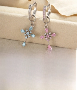 Detail of silver-plated cross pendant earrings featuring blue and pink zircon stones