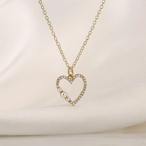 Close-up of golden heart pendant with zircon crystals and three white pearls