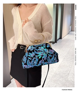 Blue-purple sequin shell bag with golden metal ring handle shown on a fashion model