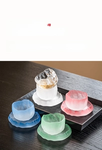 Macro shot of colorful frosted glacier glass teacups and petal saucers on wooden tray