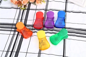 Sei clip alimentari colorate in plastica semitrasparente su sfondo a scacchi bianchi